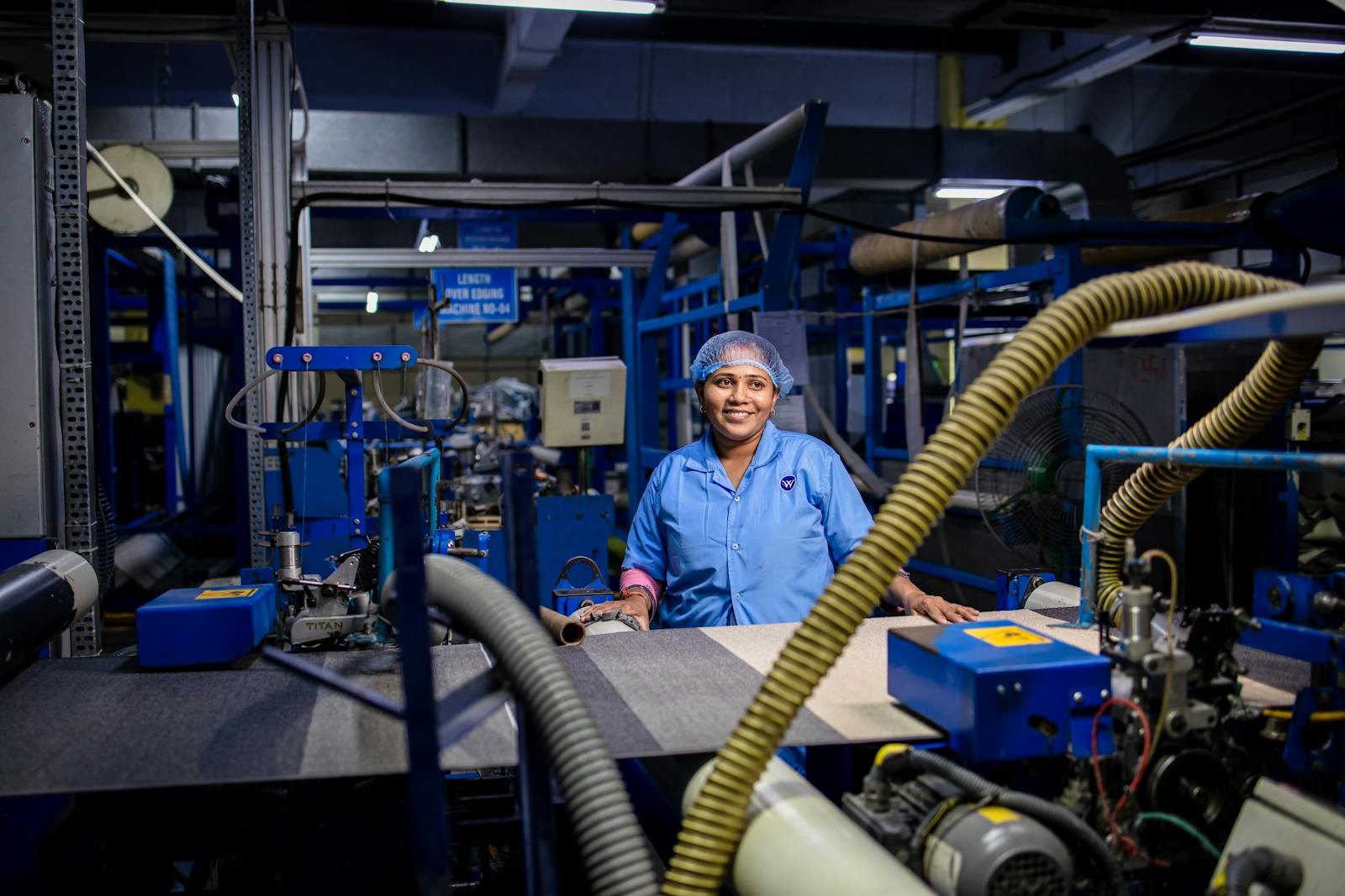 Modern manufacturing floor with operators at automation cells. Clean composition, hi-vis vests, no faces visible.
